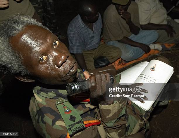 Senior commander of the Ugandan rebel group the Lord's Resistance Army, Vincent Otti shines a torch on an LRA document during a rare appearance in...