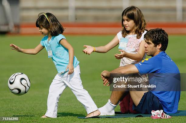 Juninho Pernambucano of Brazil takes a rest with his daughters during the Brazil National Football Team training session for the FIFA World Cup...