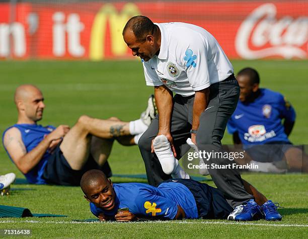 Robinho of Brazil gets some help from an assistant coach with his stretching exercises during the Brazil National Football Team training session for...