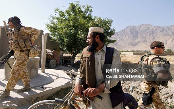 British soldiers of the International Security Assistance Force stand guard during the distribution of school bags to Afghan children in the Bagrami...