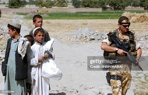 British soldier of the International Security Assistance Force stands guard during the distribution of school bags to Afghan children in the Bagrami...