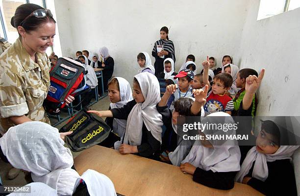 British soldier of the International Security Assistance Force distributes school bags to Afghan children in the Bagrami district on the outskirts of...