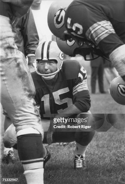 American professional football player Bart Starr, quarterback for the Green Bay Packers, crouches down in a huddle and discusses the upcoming play...