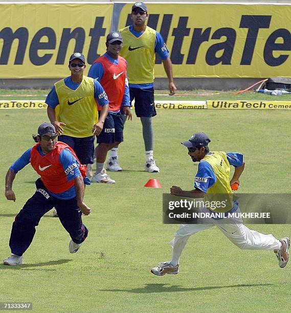 Teammates Suresh Raina, Ramesh Powar and Yuvraj Singh watch Indian cricketer Mohammad Kaif diving to avoid being stopped by teammate M. S. Dhoni from...