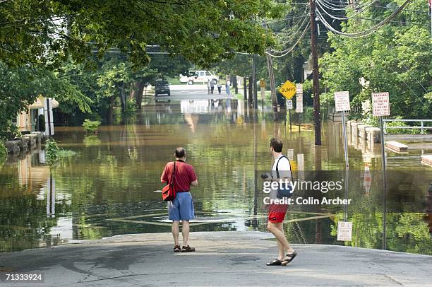 Residents and tourists stop to photograph rising water from the Delaware and Raritan Canal and the Delaware River flood South Union Street June 29,...