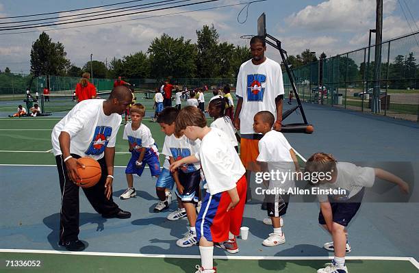 Chris Paul of the New Orleans/Oklahoma City Hornets, with an assist from Rip Hamilton, of the Detroit Pistons, demostrates dribbling skills to...