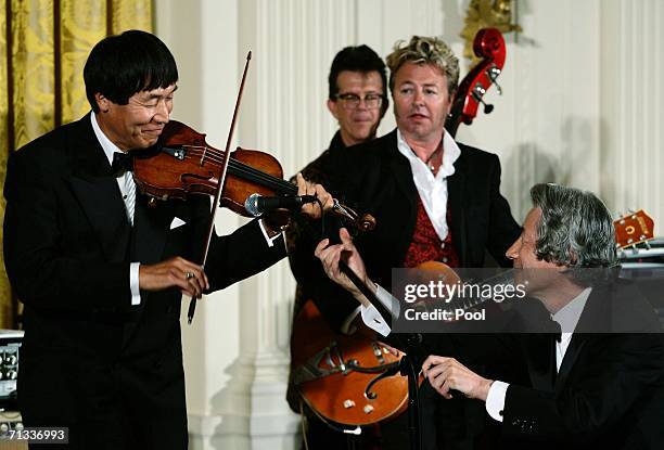 Japanese Prime Minister Junichiro Koizumi adjusts the microphone for Shoji Tabuchi , a country music entertainer, as The Brian Setzer Orchestra...