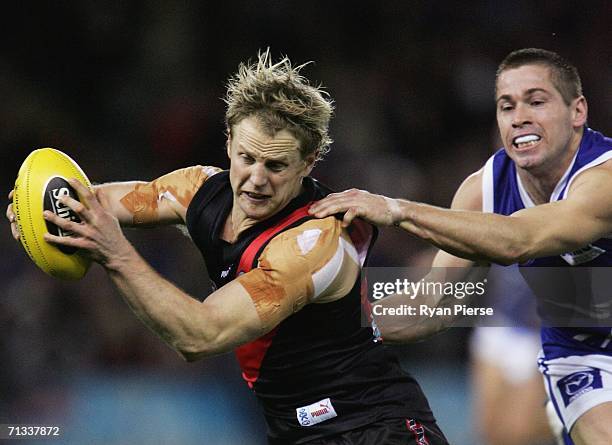 Mark Johnson of the Bombers is tackled by Shannon Grant of the Kangaroos during the round thirteen AFL match between the Kangaroos and Essendon...