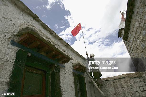 Tibetan man installs a Chinese national flag over a Tibetan village to celebrate the newly built Qinghai-Tibet Railway on June 30 in Dangxiong...