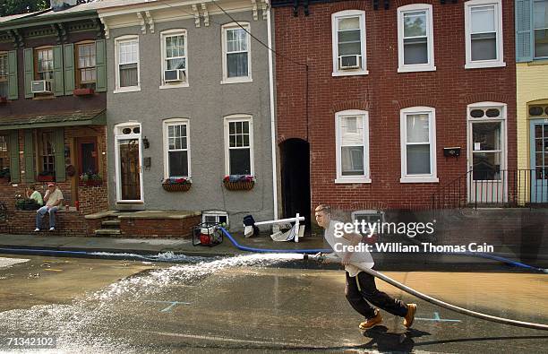 Chase Kriens of Lambertville, New Jersey pulls a hose that is pumping water from a basement as the flooding begins to recede June 30, 2006 in...