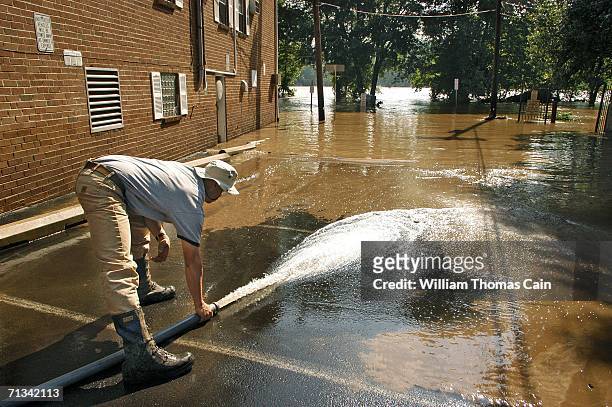 Johnny Fresco of the New Hope Fire Company hoses mud from a parking lot as the Delaware River recedes June 30, 2006 in New Hope, Pennsylvania. Damage...