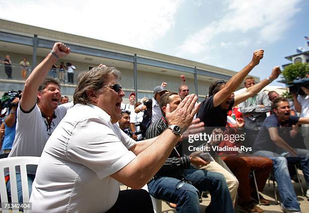 Mercedes Motorsport director Norbert Haug cheers with other fans as they watch the Germany v Argentina world cup match in the paddock during practice...