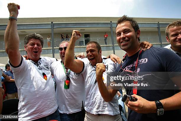 German TV presenter Kai Ebel cheers with other fans as they watch the Germany v Argentina world cup match in the paddock during practice for F1...