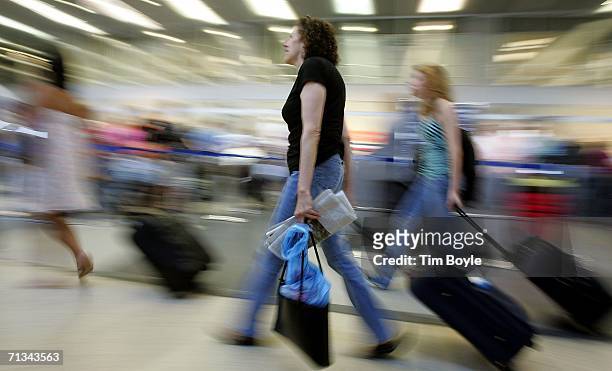 Travelers with wheeled luggage hustle through Terminal 3 June 30, 2006 at O'Hare International Airport in Chicago, Illinois. Heavy holiday travel is...