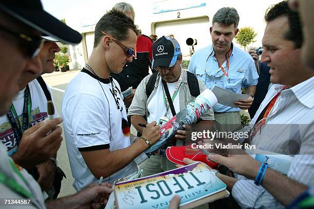 Michael Schumacher of Germany and Ferrari signs autographs in the paddock while wearing a classic German football jersey after practice for the...