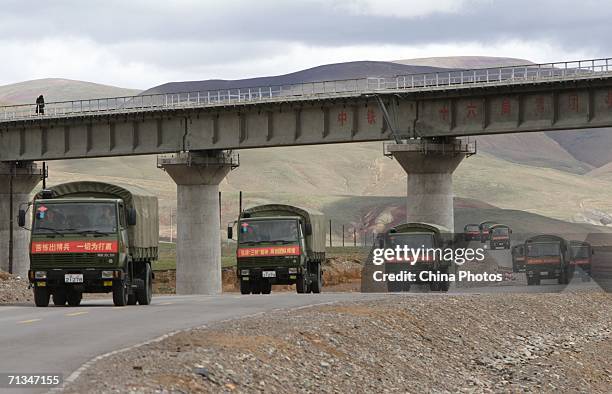 Trucks transporting military materials run below a viaduct of the Qinghai-Tibet Railway on June 30, 2006 in Golmud of Qinghai Province, China. The...