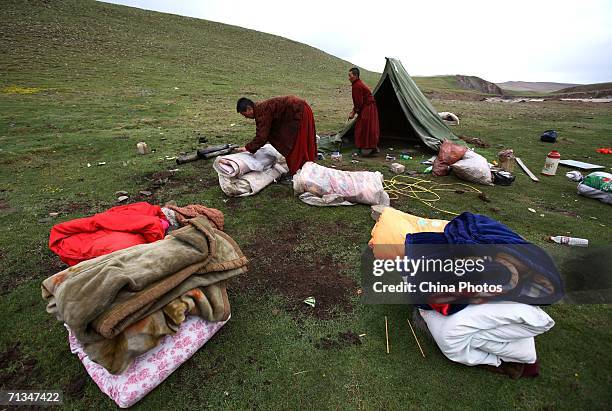 Monks and nuns pack up belongings in their camp at the mountain foot of Tanggulashan Mountain during their pilgrimage on June 30, 2006 in Golmud City...