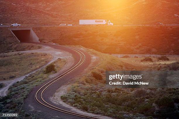 Trucks on Interstate 15 in Cajon Canyon pass railroad tracks near the San Andreas Fault at sunrise on July 1, 2006 near San Bernardino, California....