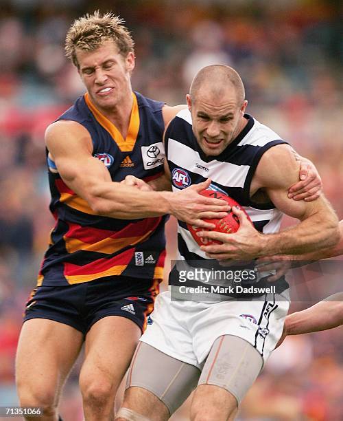 Scott Thompson of the Crows tackles Tom Harley of the Cats during the round 13 AFL match between Adelaide and Geelong at AAMI Stadium July 2, 2006 in...