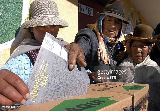 Una mujer indigena , uno de los jurados electorales de la mesa de votacion, ayuda a introducir su voto en la urna a un votante indigena el 02 de...