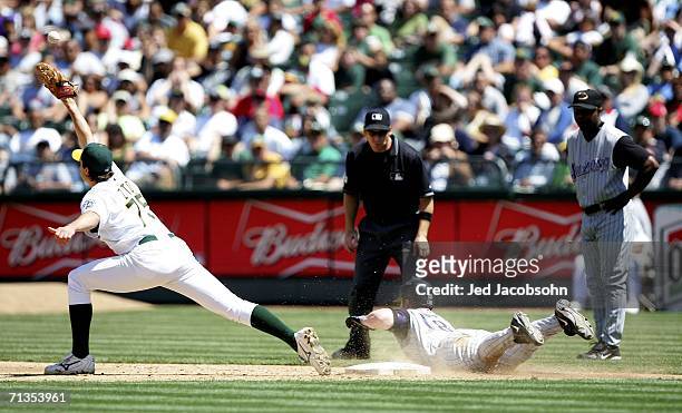 Chad Tracy of the Arizona Diamondbacks slides in safe at first on a fielding error as Barry Zito of the Oakland Athletics waits for the throw in the...