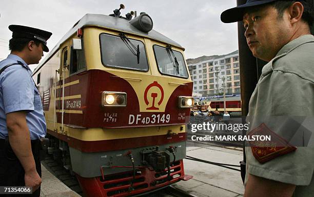 Police and rail workers watch as a new engine is connected to the first train to travel from Beijing to the Tibetan capital Lhasa, in the city of...