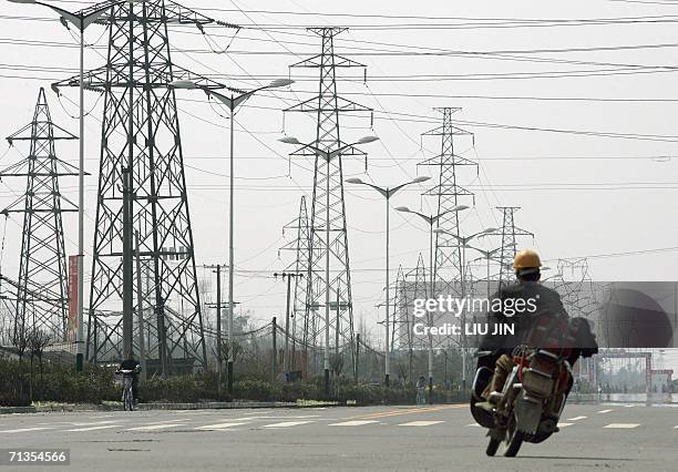 Electricity grids stand along a road as a motorbike rider wheels past in the outskirts of Chengdu, the capital of southwestern province of Sichuan,...