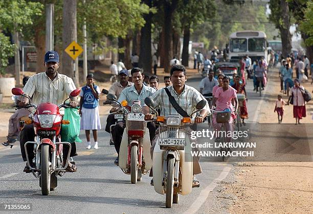 Sri Lankan commuters make their way on the main street of the rebel-held town of Kilinochchi, some 250 kilometers north of Colombo, early 03 July...