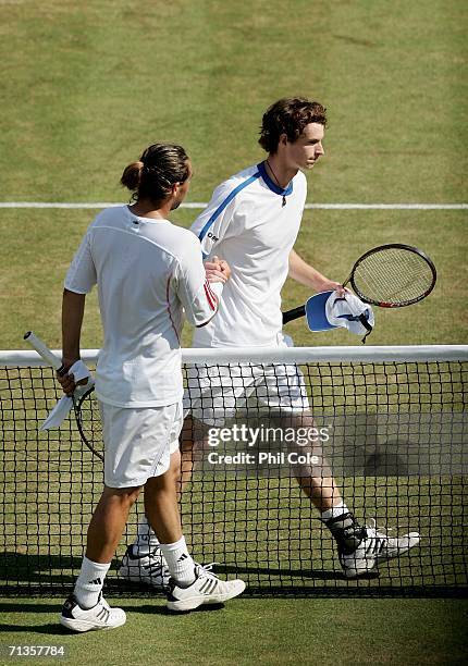 Andy Murray of Great Britain shakes hands with Marcos Baghdatis of Cyprus after losing his match to Marcos during day seven of the Wimbledon Lawn...