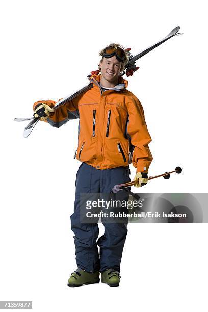 portrait of a young man holding skis and ski poles - ski boot stock pictures, royalty-free photos & images