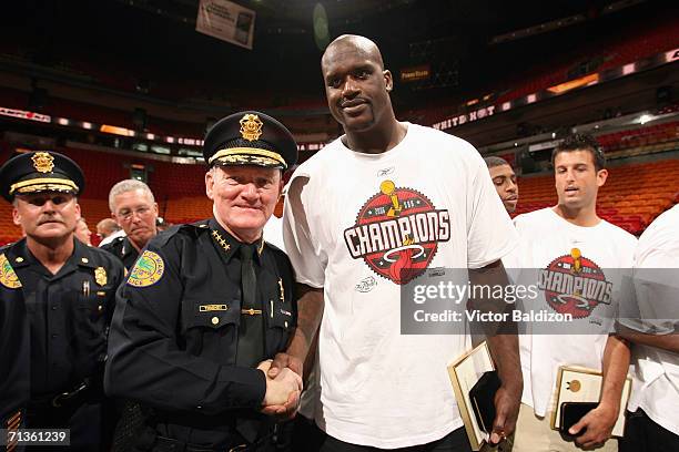 Shaquille O'Neal of the Miami Heat poses for a photo with a member of the Miami police department after receiving "The Key to the City" as part of a...