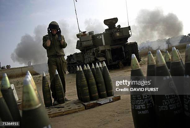 An Israeli soldier covers his ears as a mobile artillery unit fires a 155 mm round at the northern Gaza Strip from a stretch of farmland located near...