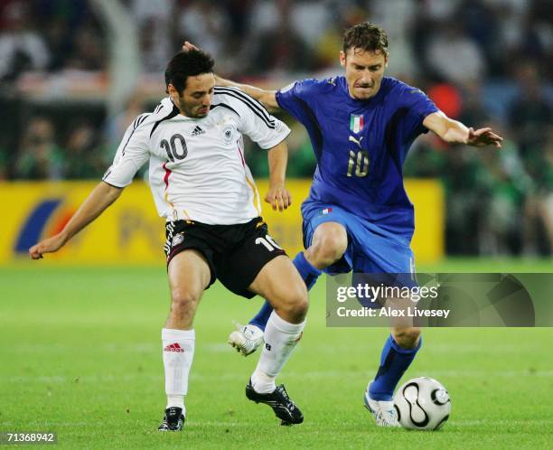 Oliver Neuville of Germany battles for the ball with Francesco Totti of Italy during the FIFA World Cup Germany 2006 Semi-final match between Germany...