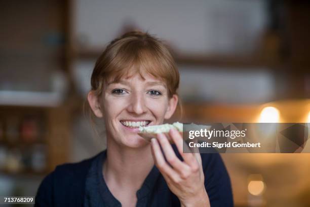 young woman eating bread with cream cheese - eating cheese stock-fotos und bilder