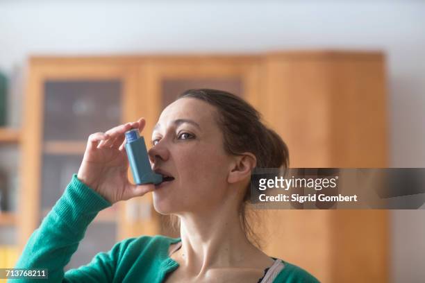 woman using asthma inhaler - sigrid gombert stock-fotos und bilder