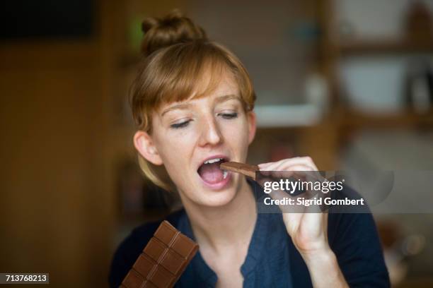 young woman eating chocolate - chocolat stock-fotos und bilder