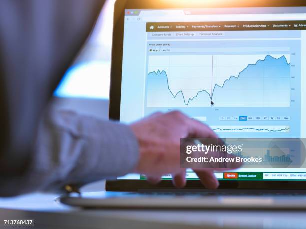 investor viewing company share price market data on a laptop computer - financial analyst photos et images de collection