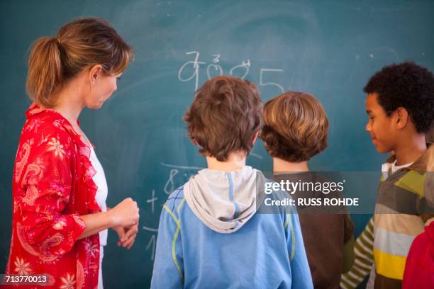 primary school teacher teaching equations to boys at classroom blackboard - teacher in front of class stock pictures, royalty-free photos & images