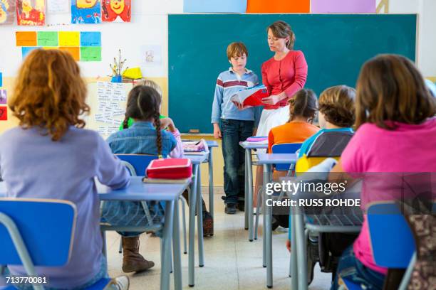 primary schoolboy reading at front of classroom - teacher in front of class stock pictures, royalty-free photos & images