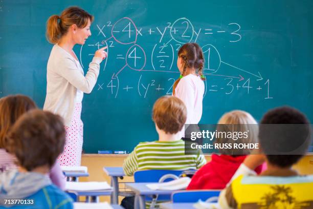 primary school teacher explaining equation on classroom blackboard - elementary school stock pictures, royalty-free photos & images