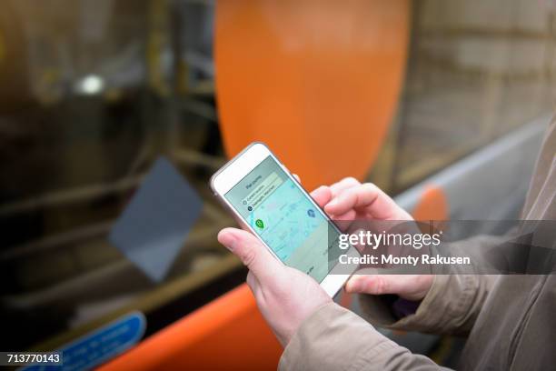 passenger using smart phone to look at bus timetable before boarding electric bus - boarding a bus stock-fotos und bilder