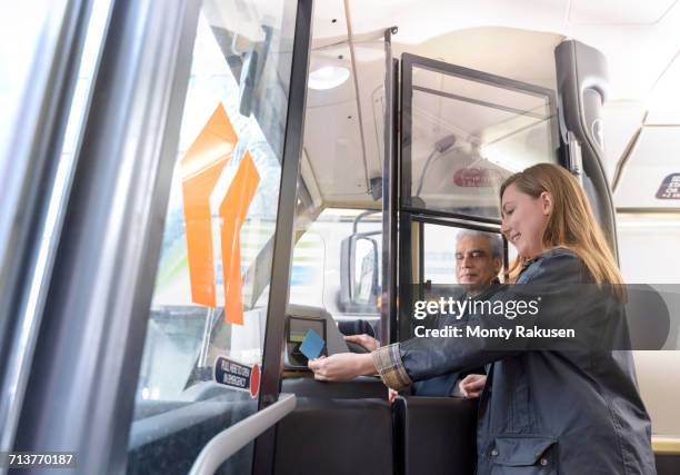 bus driver with passenger swiping travel card on electric bus - boarding a bus stock-fotos und bilder