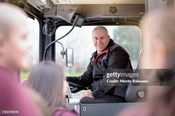 portrait of bus driver with passengers boarding electric bus - autista di autobus foto e immagini stock