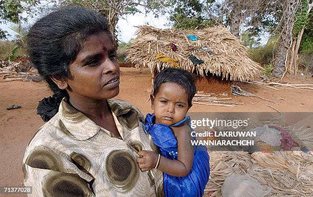In this picture taken 03 July 2006, Sri Lankan Tamil woman Srima holds her child in front of their temporary shelter at a resettlement camp near the...