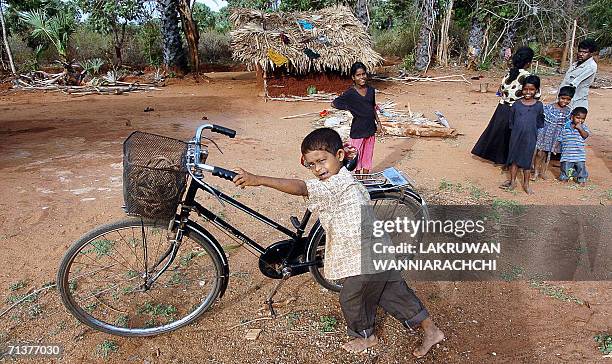 In this picture taken 03 July 2006, a Sri Lankan Tamil child pushes a bicycle near a temporary shelter at a resettlement camp near the village of...