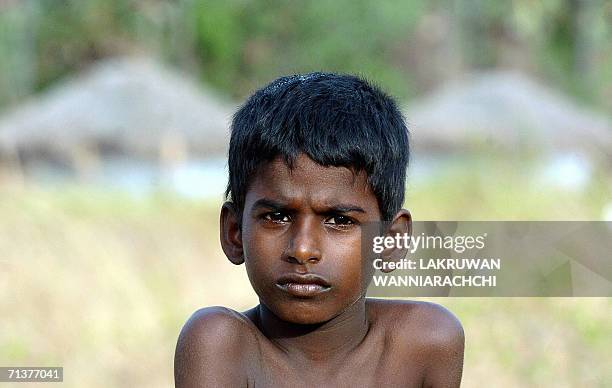 In this picture taken 03 July 2006, Sri Lankan Tamil boy Sugeewan poses for photographs as he sits outside a temporary shelter at a resettlement camp...