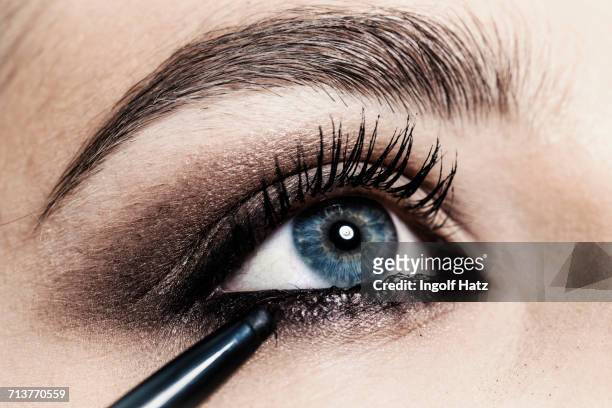 close up of eyeliner being applied to young womans eye - delineador imagens e fotografias de stock