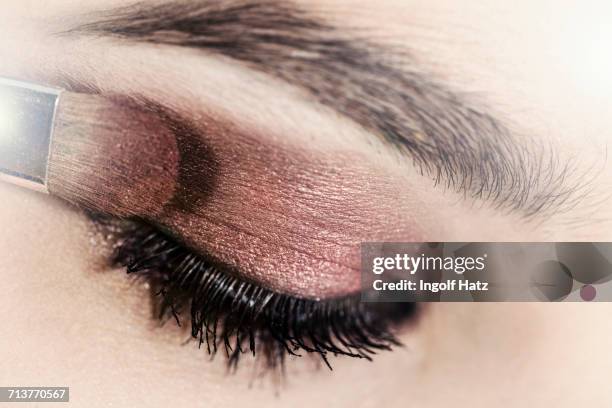 close up of eye shadow being applied to young womans eyelid - eyelid foto e immagini stock
