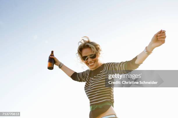 portrait of mid adult woman with arms open against sunlit blue sky - bavaria beer stock pictures, royalty-free photos & images