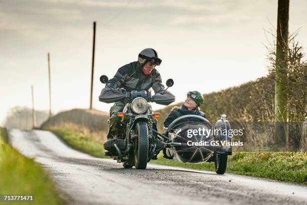 senior man and grandson riding motorcycle and sidecar along rural road - old man on motor bike stock pictures, royalty-free photos & images